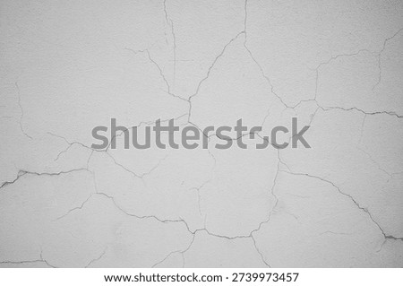 Aged light beige wall with multiple cracks. Damaged surface texture detail for renovation concept. Rough concrete plaster background.