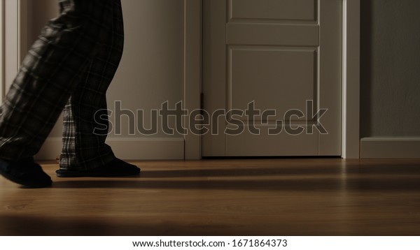 Aged man in\
pajamas walks on a home in the\
night