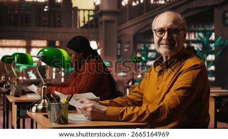 Aged man in a study area surrounded by library books and paperwork, preparing for university coursework and thesis writing with academic database materials at the campus.