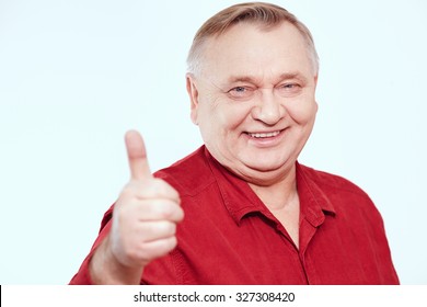 Aged Man Wearing Red Shirt Showing Thumb Up Hand Gesture And Smiling Against White Background - Happy Retirement Concept