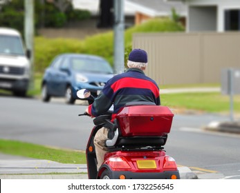 Aged Person on a Red Mobility Scooter Outdoors crossing the street 