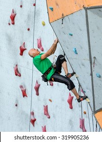 Aged Person Practicing Extreme Sport
Elderly Male Climber Makes Hard Move And Looking High Up On Outdoor Climbing Wall Sport Competitions