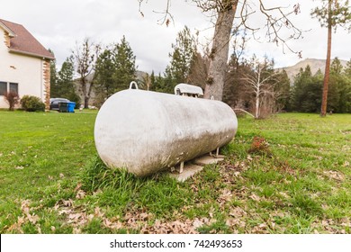 Aged Propane Tank Near A Large Home.