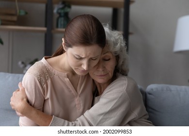 Aged retired female mother hold in arms embrace tight upset depressed young female adult kid daughter listen to confession give excuse for wrong deed. Old lady mom support comfort beloved grownup girl