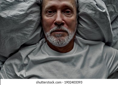 aged retired man lying in bed with opened eyes, having problems with sleep. unhappy mature old grandfather suffering from insomnia at night. - Powered by Shutterstock