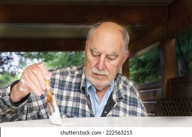 aged senior man with expressive face painting carefully  a garden  table - Powered by Shutterstock