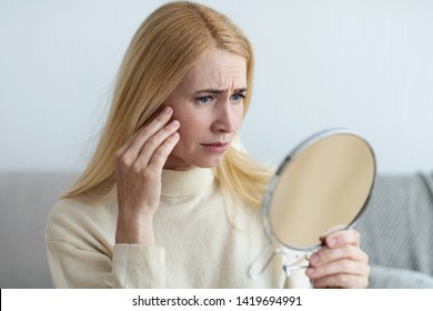 Aged Skin. Mature Sad Woman Looking At Her Wrinkles In Mirror