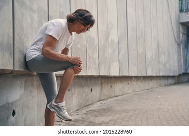 Aged Slim Woman Hurting Knee Joint While Running