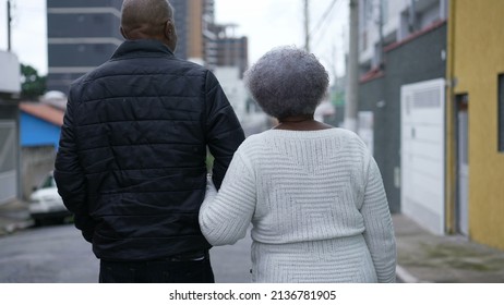 An Aged Son Walking With Elderly Mother In 80s Outside In Urban Street Going For A Walk