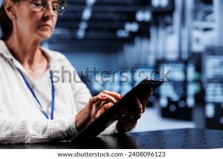 Aged technical support consultant using tablet to assess server security glitches arising due to unsecured network connections. Certified expert ensuring data center is impenetrable by virus attacks