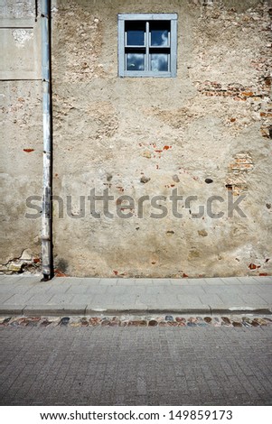 Aged weathered street wall with small window