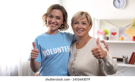 Aged Woman And Female Volunteer Showing Thumbs Up And Hugging, Retiree Help