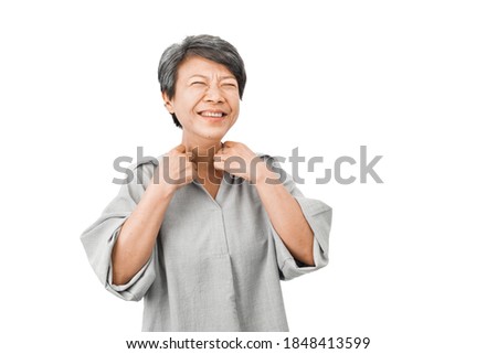 An aged woman with gray hair was embarrassed, so put her hand on the collar. And laughs, feels happy, poses at the white studio, adverts of prosthesis dental clinic procedures for the elderly.
