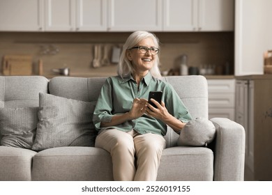 Aged woman hold smartphone at home, spend time on internet, watch videos, read news, check updates, using health apps to track physical activity, medication reminders, scheduling medical appointments - Powered by Shutterstock