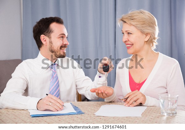 Aged woman\
signing papers for new car at home\

