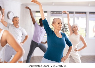 Aged woman takes part in dance class with diverse group of individuals who are enthusiastic about outdoor activities. This multinational group is actively involved in dance lesson and enjoying it. - Powered by Shutterstock