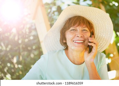 Aged Woman Talking On The Phone. Old Lady In The Park. Sunny Day, Happy Mood. Upset Senior Woman With Phone