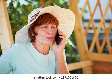 Aged Woman Talking On Phone. Old Lady In The Park. Sunny Day, Happy Mood. Upset Senior Woman With Phone