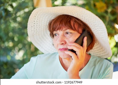 Aged Woman Talking On The Phone. Old Lady In The Park. Sunny Day, Happy Mood. Upset Senior Woman With Phone