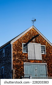 Aged wooden siding on boathouse in New England against blue sky.