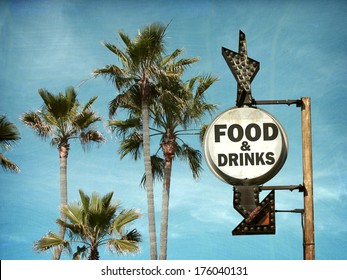   aged and worn vintage food and drinks sign on beach with palm trees                             