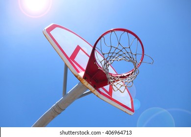 Aged And Worn Vintage Photo Of Outdoor Basketball Hoop At Beach With Bright Sun Flare                               