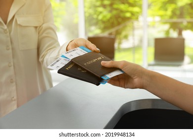 Agent giving passports and tickets to woman at check-in desk in airport, closeup - Shutterstock ID 2019948134