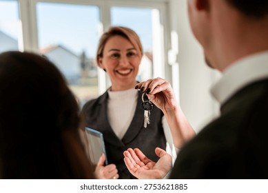 Agent handover keys of new empty, light and modern house to her customers. 