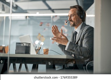 Agent in headset consulting business client online using laptop while sitting at the desk - Shutterstock ID 1769355389