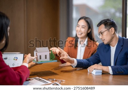 Agent presenting a house model to a young couple considering a property purchase