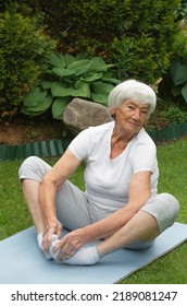 An Age-old Gray-haired Woman Does Therapeutic Exercises To Stretch The Muscles Of The Back, Spine. Stretching Of Hip Joints, Knees, Tendons, Muscles. Yoga Asana 