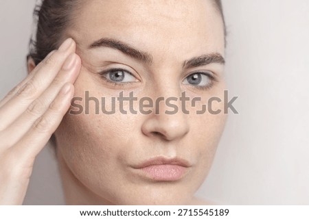 Age-related changes on the face of a middle-aged woman. First wrinkles. A woman thinks about a facelift, plastic surgery. Cropped close up