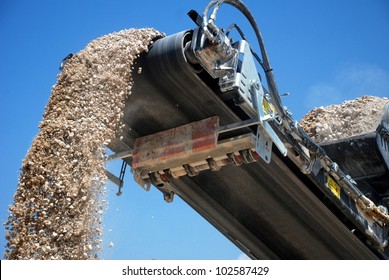 Aggregate Production By Mobile Crusher. Conveyor Belt Of A Working Mobile Crusher Machine, Close-up, With Blown Away By The Wind White Stone Dust Against A Blue Sky.