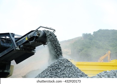 Aggregate Production By Mobile Crusher. Conveyor Belt Of A Working Mobile Crusher Machine, Close-up, With Blown Away By The Wind White Stone Dust Against A Blue Sky.