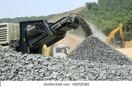 Aggregate Production By Mobile Crusher. Conveyor Belt Of A Working Mobile Crusher Machine, Close-up, With Blown Away By The Wind White Stone Dust Against A Blue Sky.