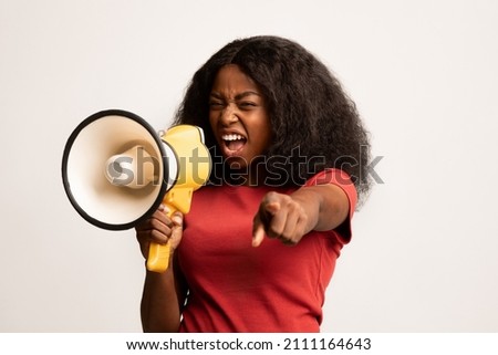 Aggressive African American Woman Shouting With Megaphone And Pointing Finger At Camera, Emotional Black Lady Leader Yelling To Loudspeaker, Making Announcement Or Sharing Demand Over White Background