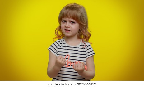 Aggressive Angry Blonde Kid Child 5-6 Years Old In T-shirt Trying To Fight At Camera, Shaking Fist, Boxing With Expression, Punishment On Yellow Studio Background. Teenager Children Girl Emotions