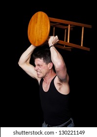 An Aggressive, Angry Man Ready To Fight With A Bar Stool In His Hands.