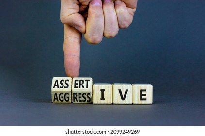 Aggressive or assertive symbol. Businessman turns wooden cubes, changes the word Aggressive to Assertive. Beautiful grey background, copy space. Business, psychological aggressive assertive concept.