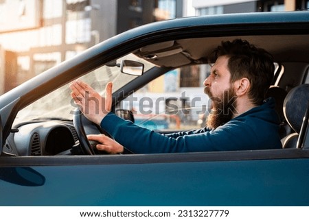 Aggressive bearded Caucasian man yelling and shouting in traffic, road rage concept 