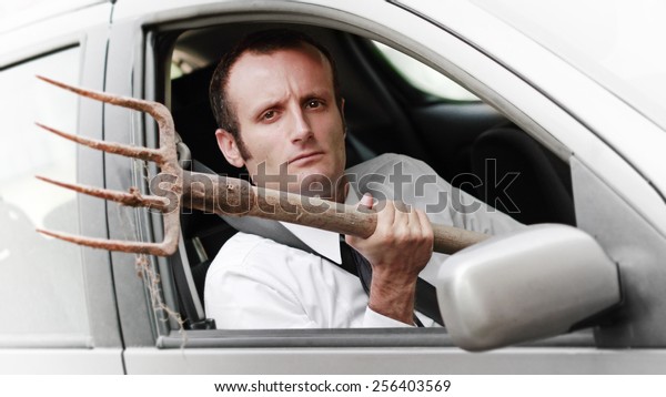 Aggressive businessman driver, with a fork inside\
the car.