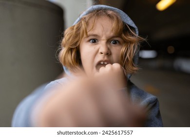 Aggressive child. Aggression kid boy fighting on street. Angry aggression kid with fist. Aggression fight kid. Bullied, physical abuse, children fighting. Aggression little boy. Kids bad behavioral.