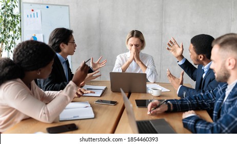 Aggressive Colleagues Shouting At Unhappy Victimized Business Lady Sitting At Desk In Modern Office. Problems And Disagreement At Work, Business Team Communication, Corporate Bullying Issue. Panorama