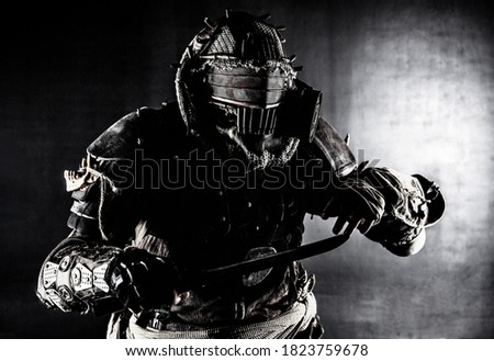 Aggressive and evil humanoid monster or creature of post apocalyptic, poisoned by dangerous pollution world wearing tattered rags and gas mask, brandishing bloodstained machete studio shoot on white