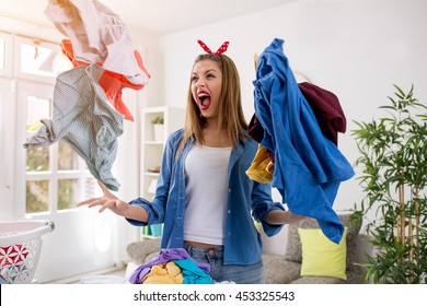 Aggressive frustrated young woman throws laundry in the air