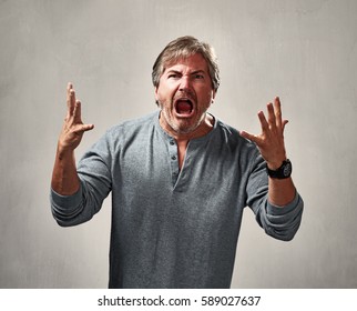 Aggressive mad man portrait over gray background - Shutterstock ID 589027637