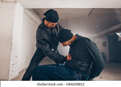 Aggressive Man Hitting A Tied Up Man In The Stomach In The Garage