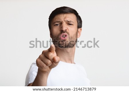 Aggressive Man Pointing Finger Looking At Camera Blaming You Standing Posing Expressing Negative Emotions Over White Studio Background. You Are Next Concept