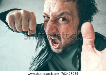 Aggressive man punching with fist during the fight, from victim's point of view. Violence and crime concept.