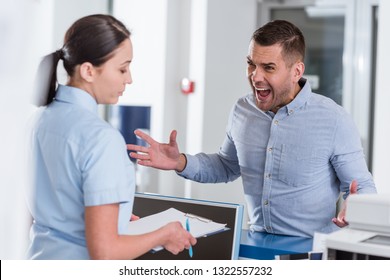 Aggressive man yelling at nurse in clinic - Shutterstock ID 1322557232